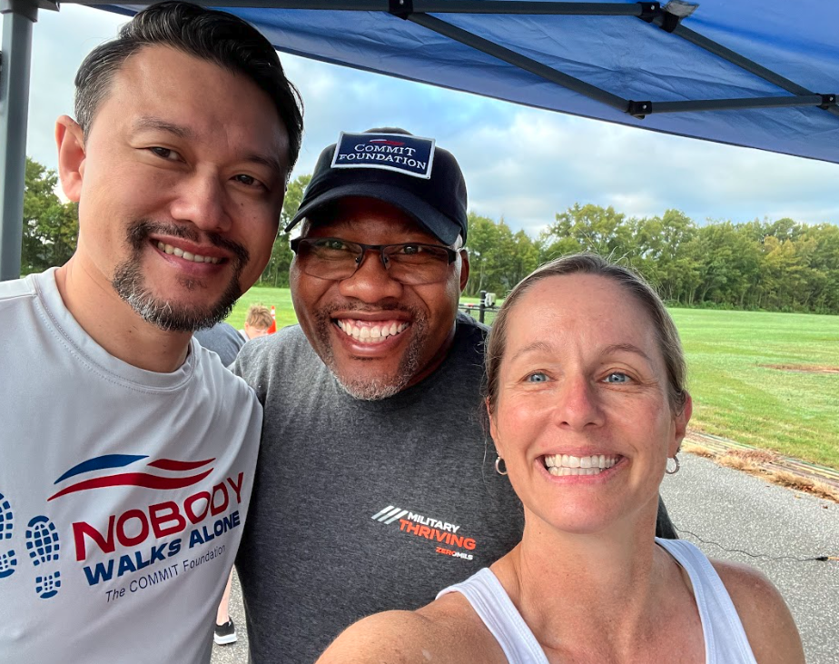 Group selfie at a 'Nobody Walks Alone' event, with Commit Foundation and Military Thriving shirts.