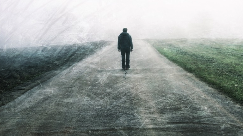 Person standing alone on an empty, foggy road.