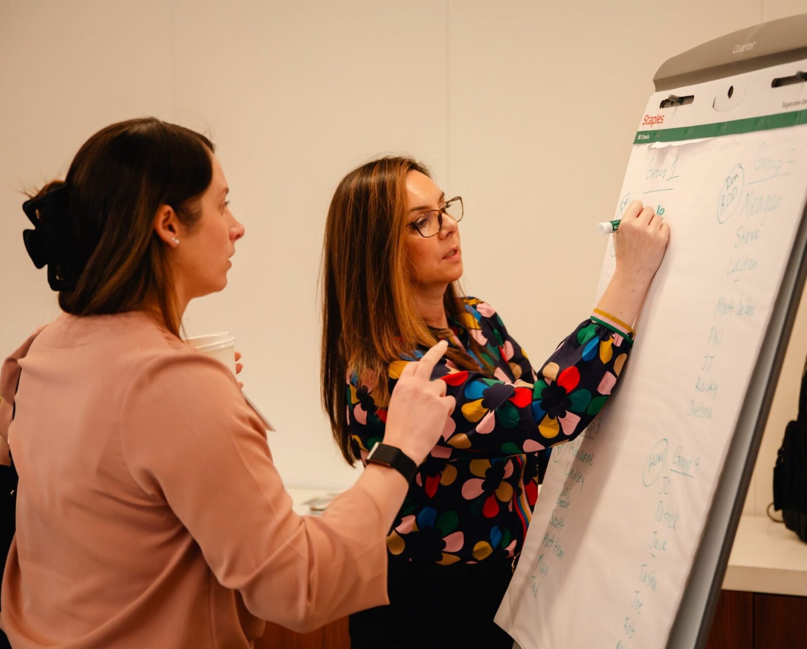 Two people discussing and writing on a whiteboard during a meeting